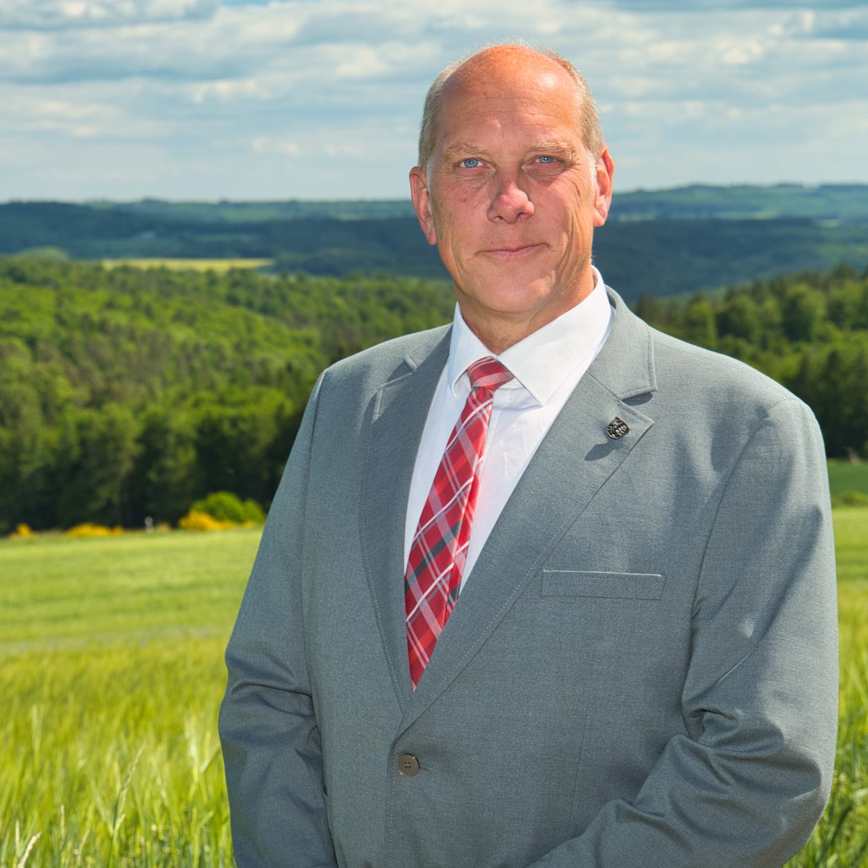 Bürgermeister Volker Diefenbach mit Anzug und roter Krawatte vor einem traditionellen Gebäude in Heidenrod.